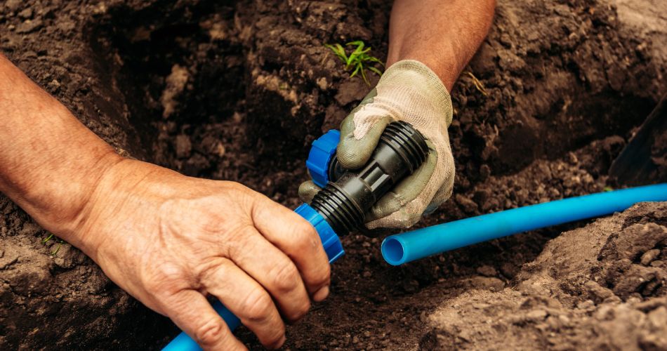 Closeup of hands installing an irrigation system underground.